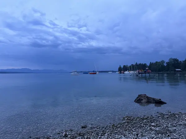 Dunkle Sturmwolken über dem See, das Wasser in kühlem Blau
